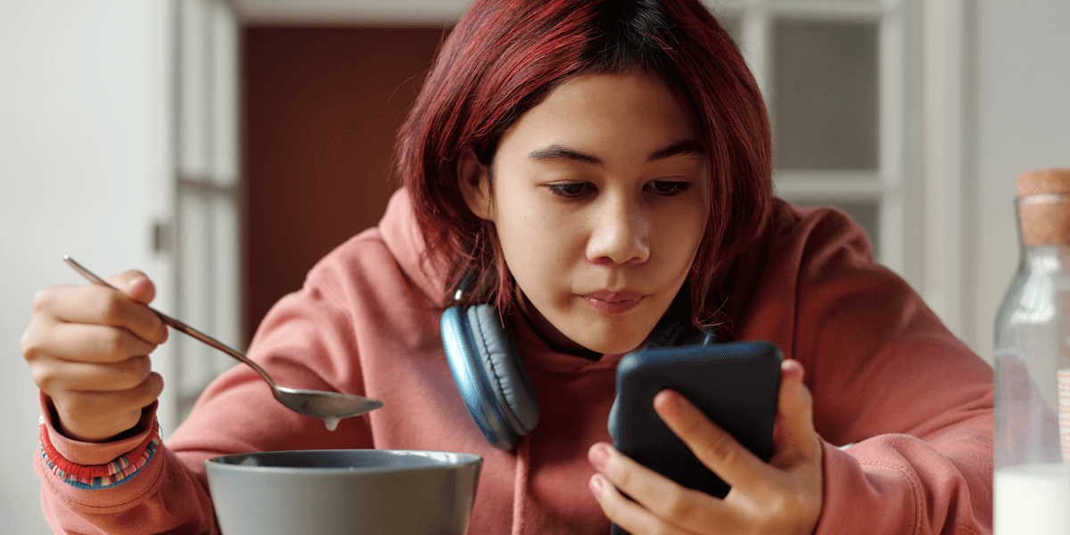 Girl on her phone while eating breakfast