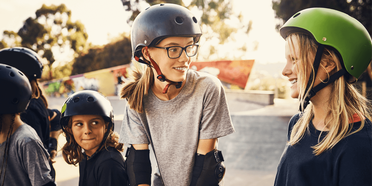 A group of adolescent girls in skateboarding helmets and gear
