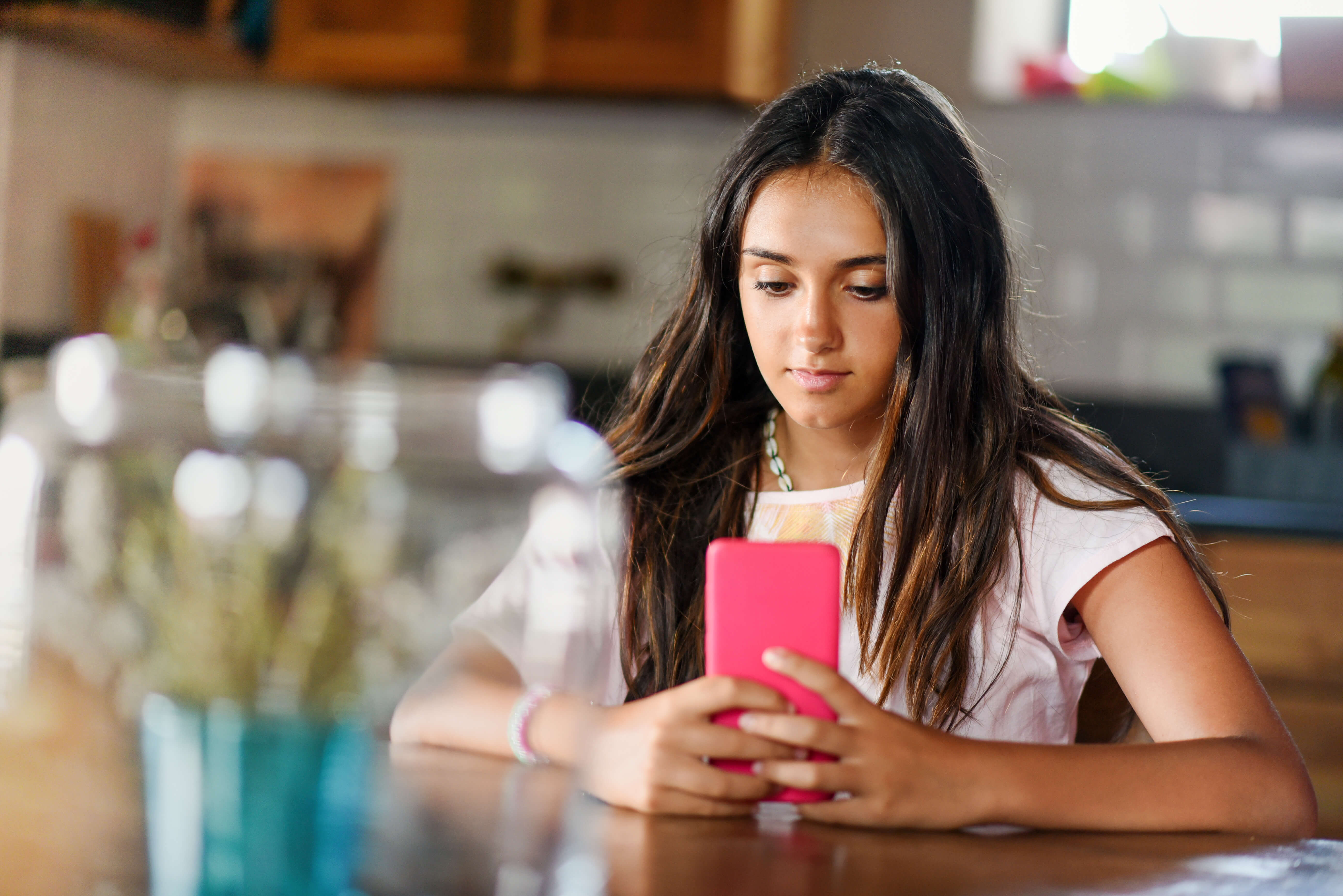 Teen looking at a phone in a home kitchen